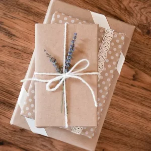 3 petits paquets cadeaux beige et blanc entourés d'une ficelle avec un brin de lavande